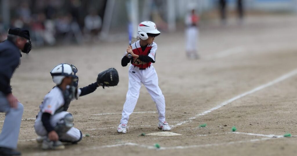 野球試合中で打者が構えている。捕手は球を受けようとしている。主審も球に集中している場面